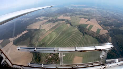 mirando por la ventana de un planeador sobre campos y bosques, el punto de vista del piloto desde una cabina