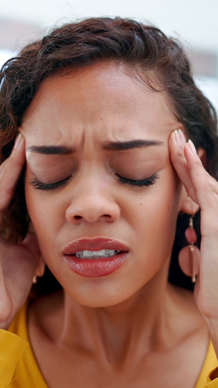 Young Woman Suffering From a Headache and Rubbing Her Temples