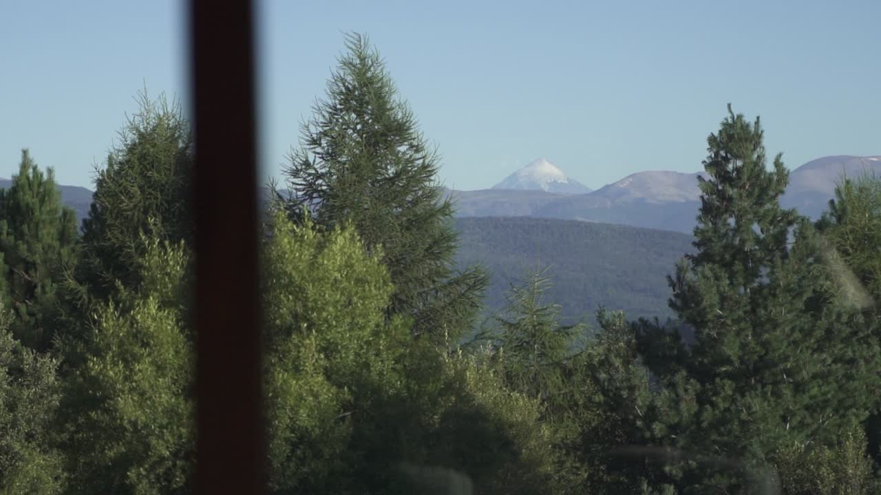 Impresionante vista desde la ventana de una gran montaña nevada y vegetación de árboles a cámara lenta y 60 fps