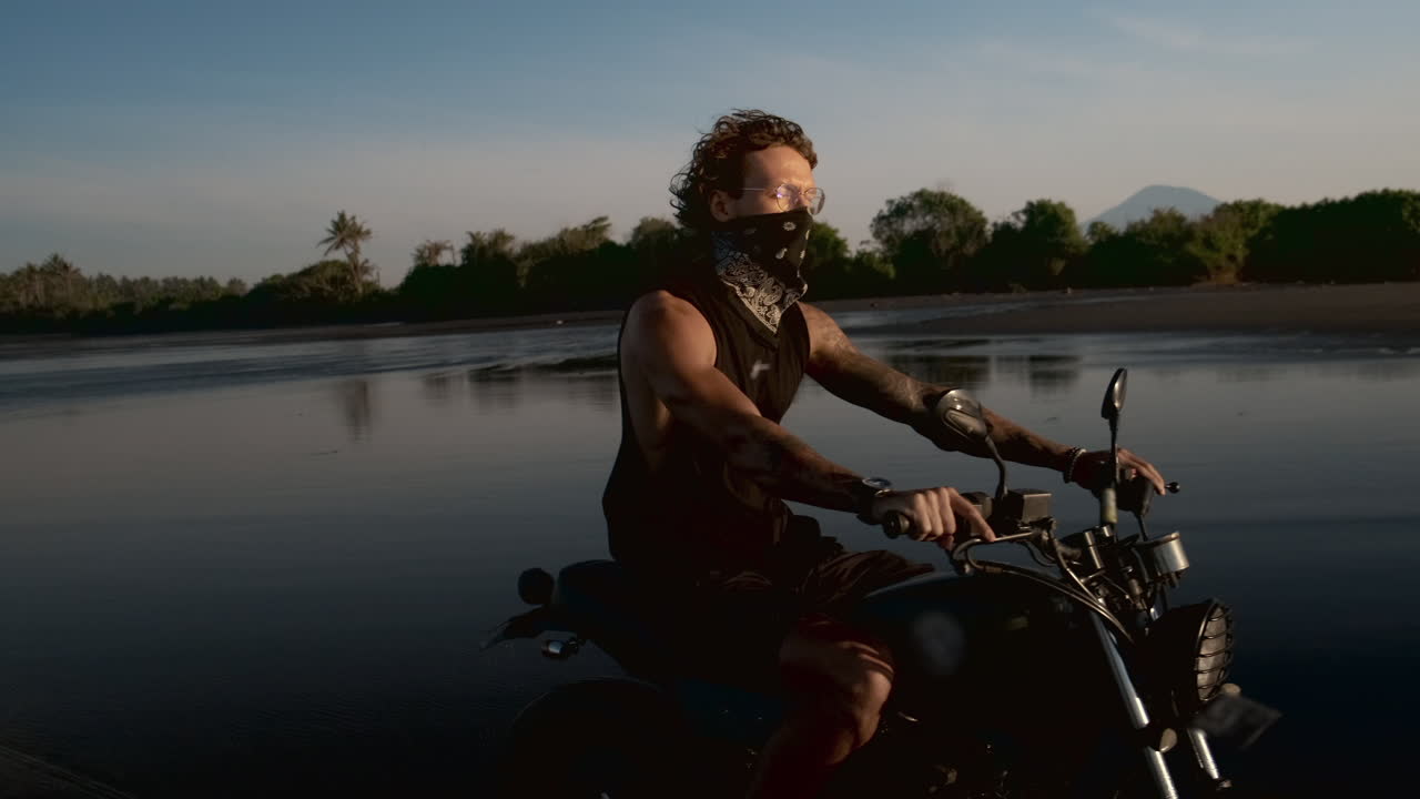 Man Riding a Motorcycle on a Beach at Sunset