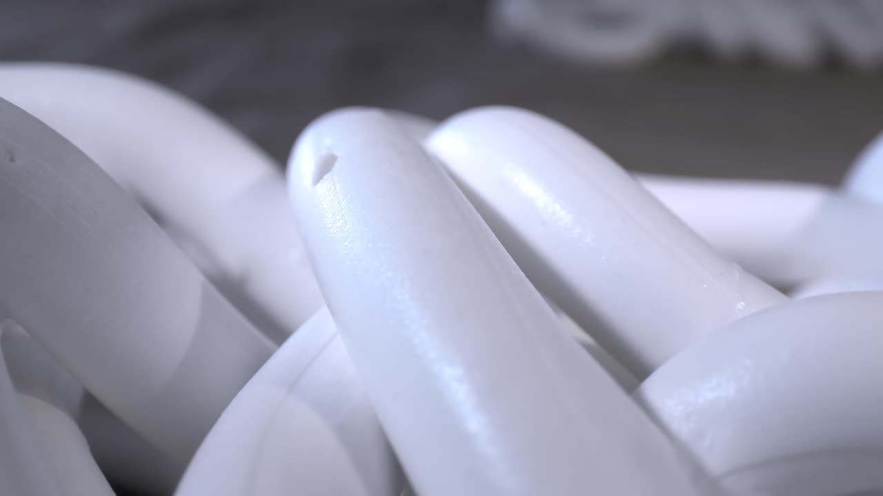 moviéndose lentamente hacia la derecha, una vista macro detallada de una sección de material blanco con un agujero en la parte superior que descansa sobre otras capas diagonales debajo