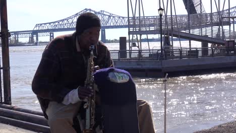 un músico sin hogar toca música de jazz a lo largo del río mississippi en nueva orleans