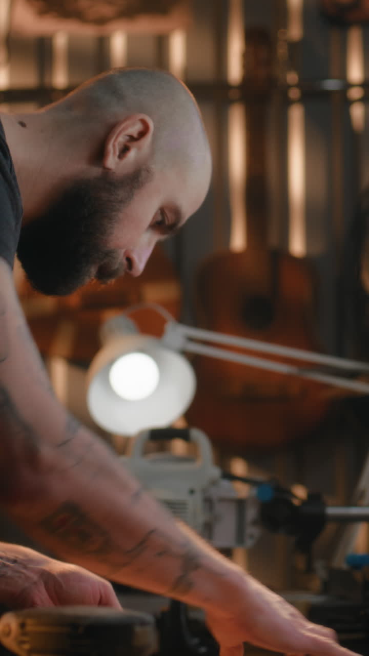 woodworking Master Attaches the Neck of the Guitar to Guitar Body Professional Male Carpenter Attaches the Neck of the Guitar to Guitar Body Woodworking Master Craftsman Makes Wooden Musical Instrument in Modern Workshop Shot