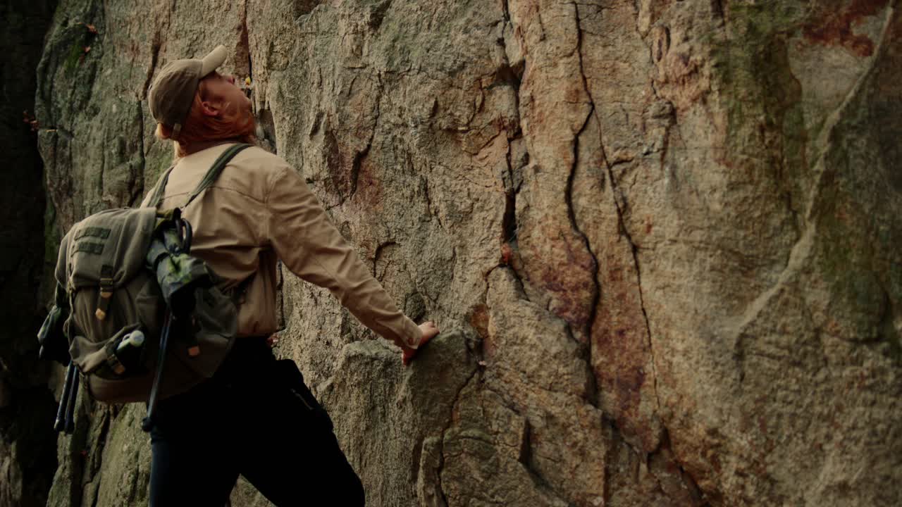 excursionista sosteniendo una mochila de pie junto a una enorme roca mirando hacia arriba, vogelberg, dürnstein
