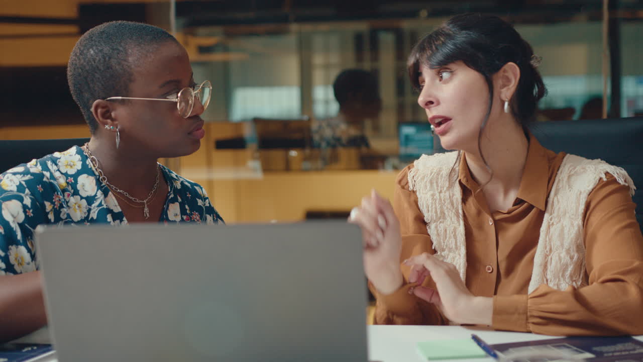 Female Colleagues Using Laptop and Discussing Work in Modern Office