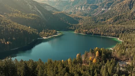 Drone-view-on-small-lake-in-the-middle-of-the-forest,-Dolomites-in-the-Italian-Alps-in-winter-season