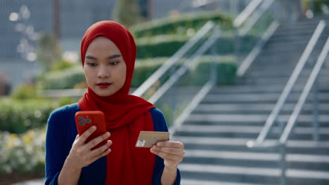 woman in hijab making an online payment with smartphone and credit card