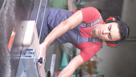 carpenter cutting wood with a table saw in a workshop