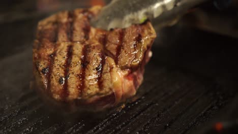 slowmo - tongs turning over steak cooking on a bbq pan - close up detail