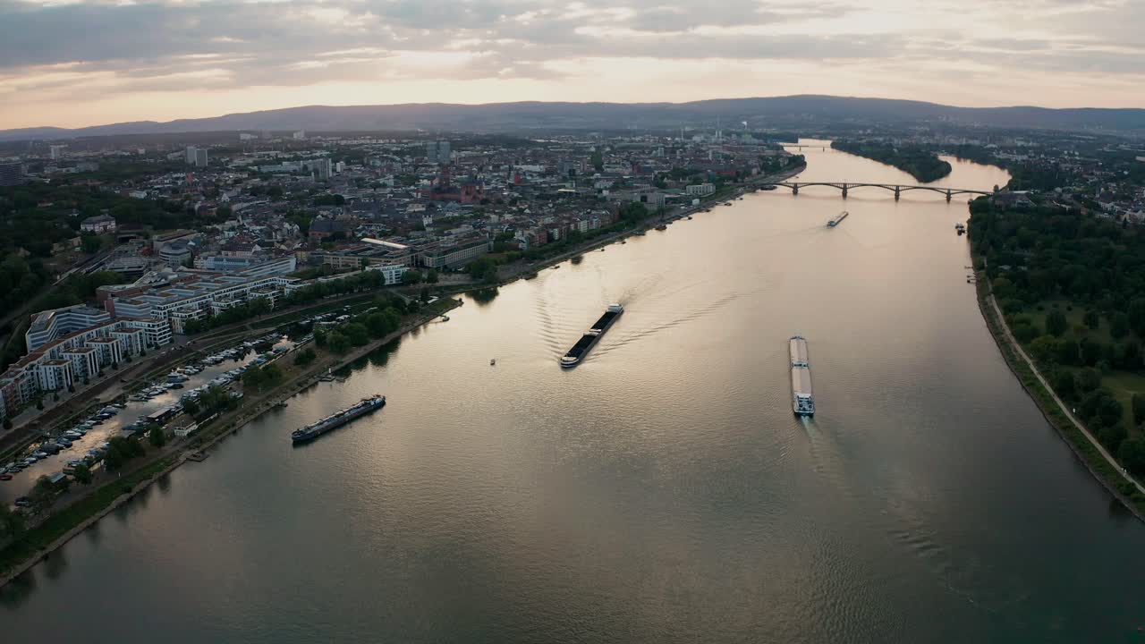 Summer Sunset over Mainz approaching the Dom church from Rhine river with container cargo ships and bridge in the background