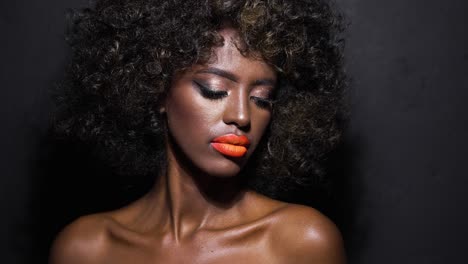 mujer negra elegante con lápiz labial naranja y afro