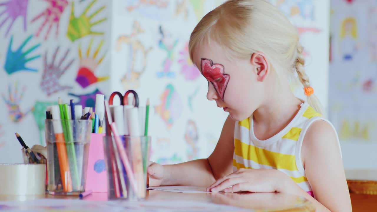 축제 메이크업을 한 소녀가 게임 룸에서 그립니다.