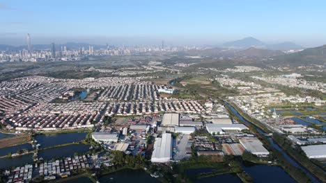 hong kong and shenzhen border line over hong kong rural houses with shenhzen skyline in the horizon, aerial view