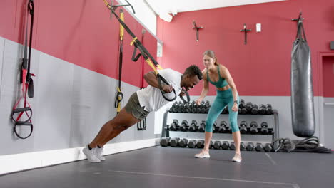 Fit-personal-trainer-assisting-an-African-American-man-at-the-gym