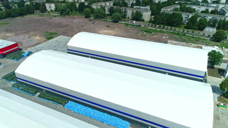 drone view over two large white storage facilities on the edge of a residential area