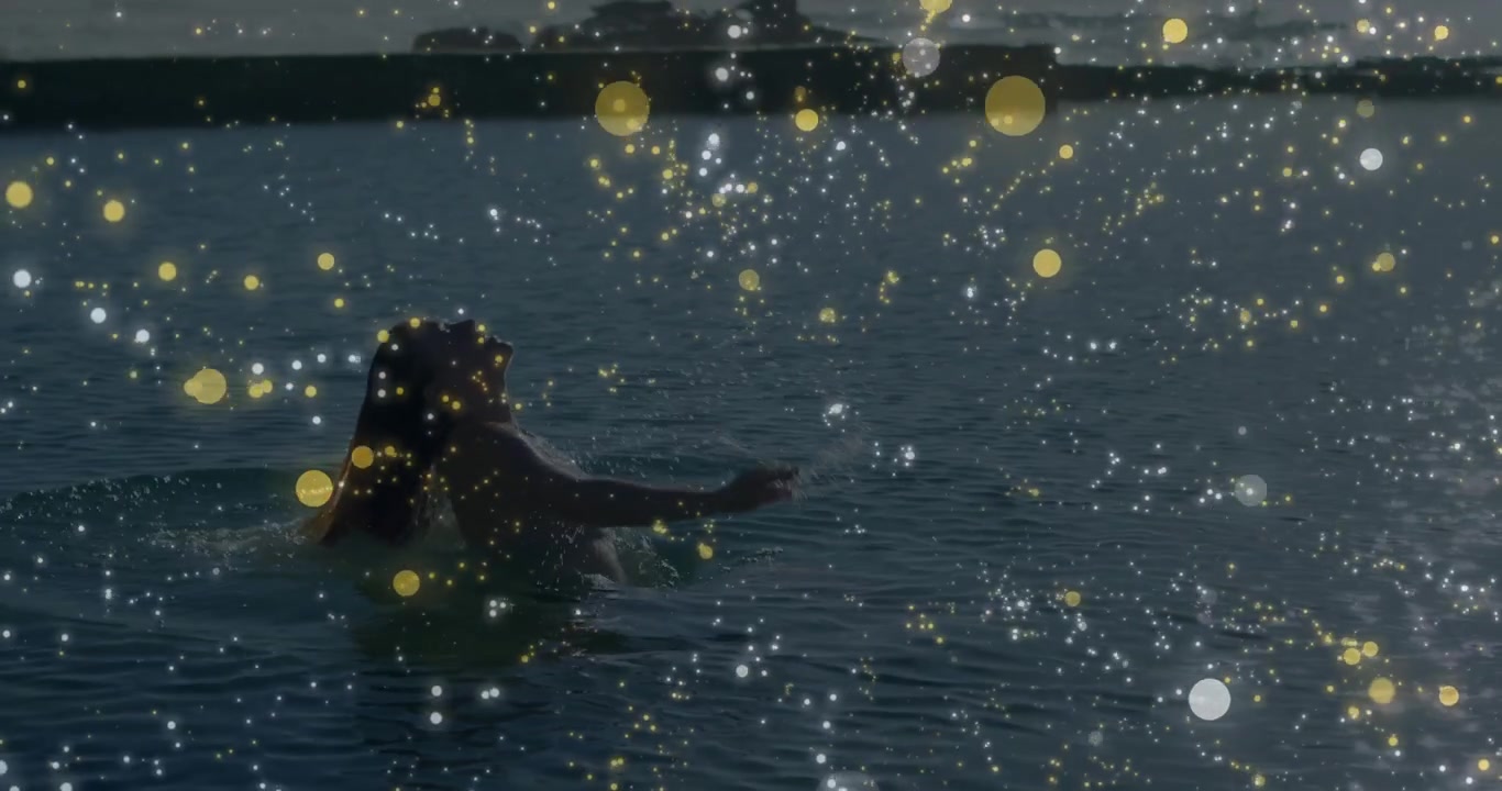 Turning toward camera woman drifting in sea floating and swimming in wellness with golden bokeh