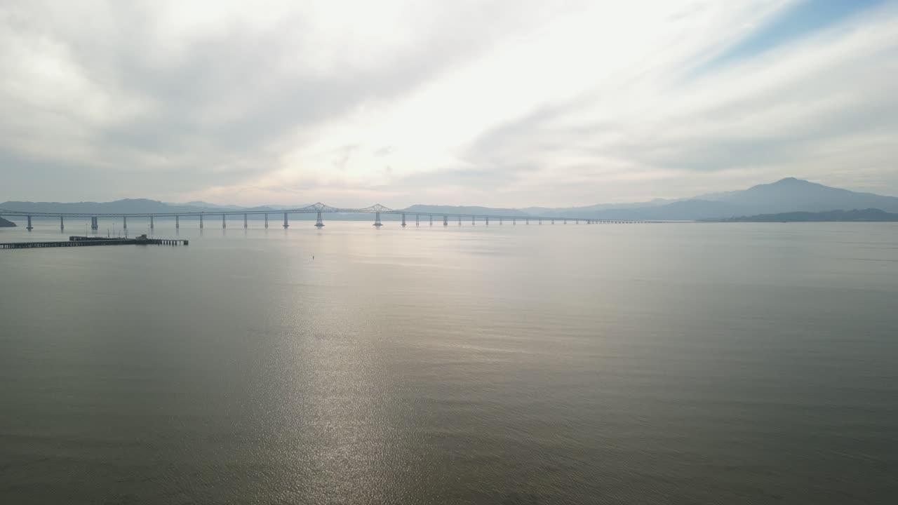 Drone descends to water with Richmond Bridge from Point Molate Beach Richmond California USA