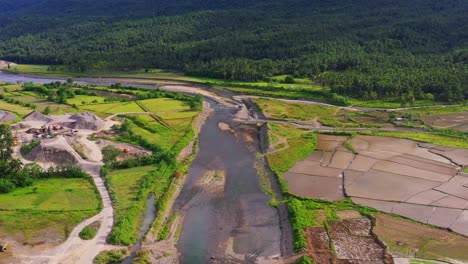 shallow stream flowing by the farmland with quarry crushed stone area during summer