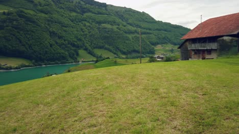 Traditional-alpine-hut-at-idyllic-emerald-lake,-pan-shot