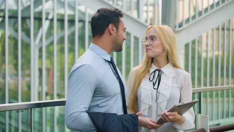 happy businessman meeting with businesswoman in modern office terrace watching digital tablet and talking business - slow motion