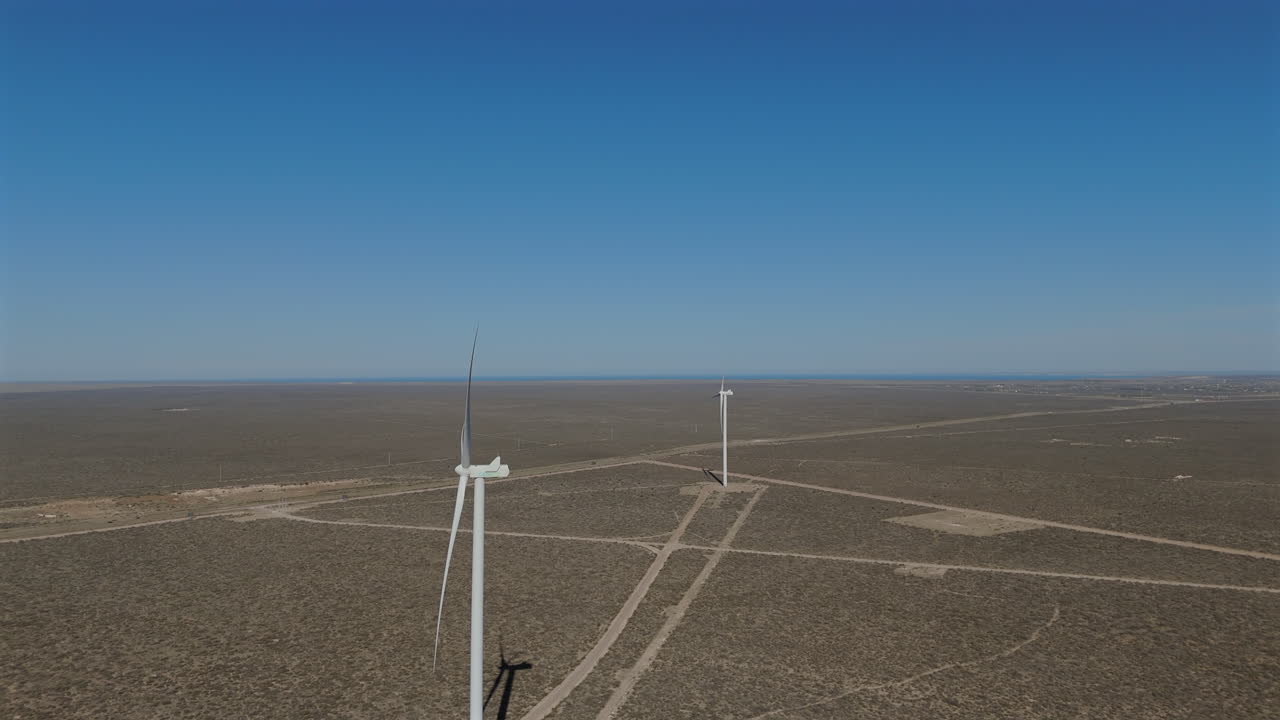 Slow motion aerial view side profile two energy windmills within wind farm Argentina