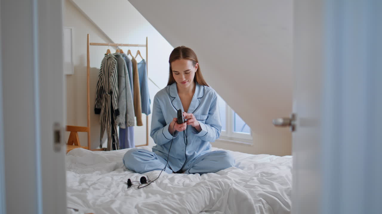 Positive lady sitting bed using music player at morning. Girl resting at weekend