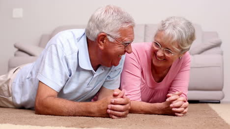 una pareja de mayores acostada en el suelo charlando.