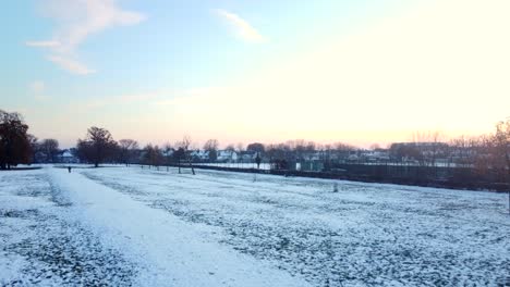 Drone-shot-white-snow-covered-park-and-field-in-English-urban-town