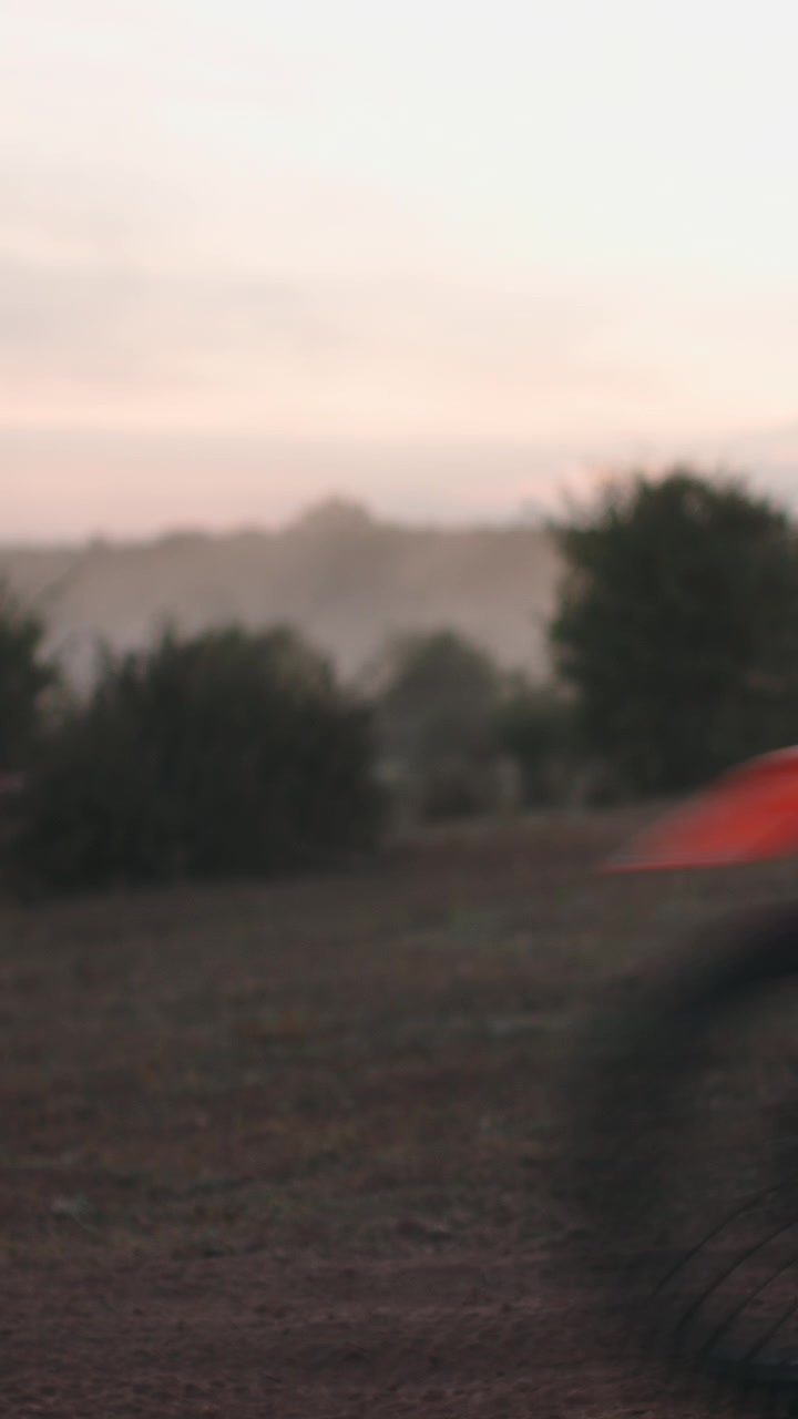 Pilota di motocross che sfreccia attraverso un campo polveroso al tramonto