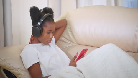 woman relaxing on couch with headphones and phone