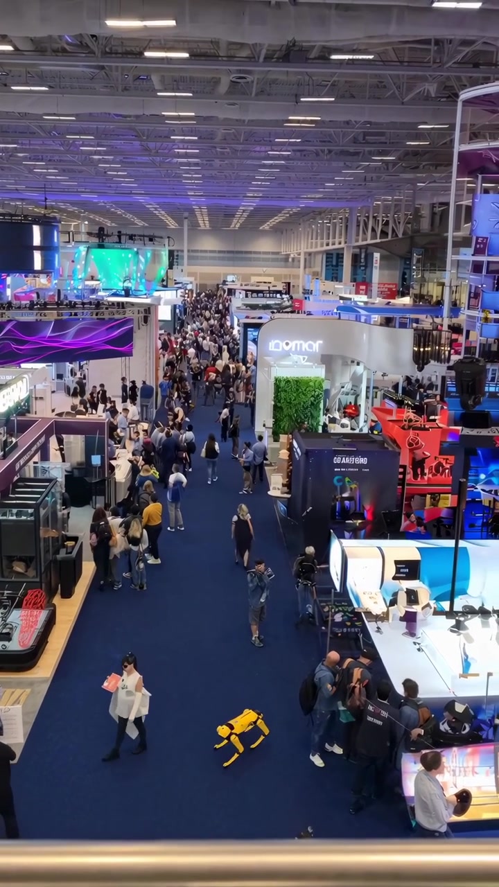 Area espositiva affollata di una fiera tecnologica con stand degli espositori