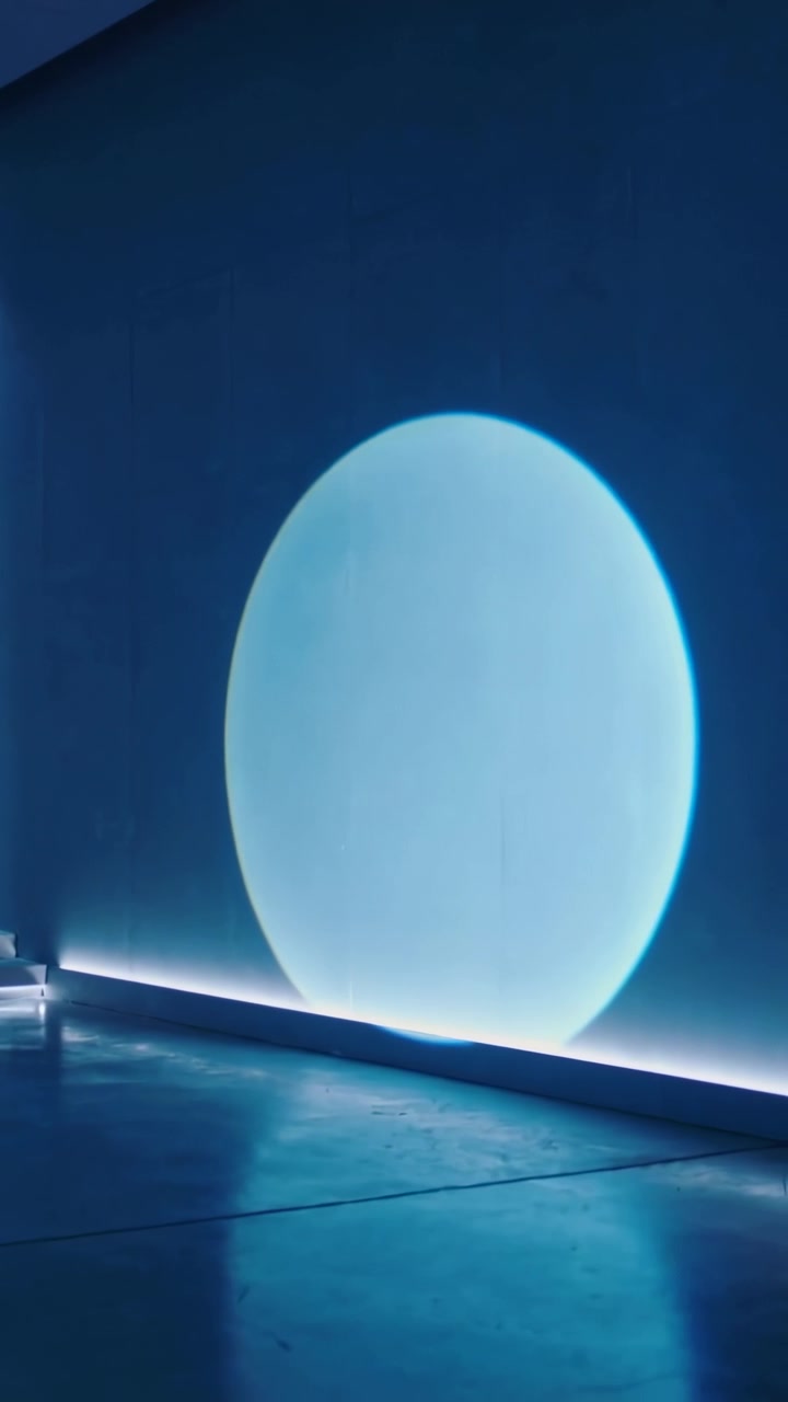 Video verticale: Disco blu che si alza sopra la base LED, espandendosi lungo la parete della galleria e illuminando la parte inferiore della parete.
