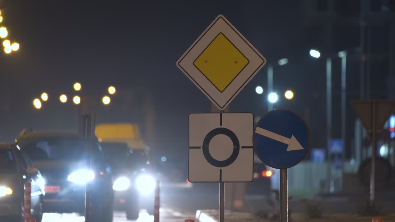 señales de carretera de rotonda con coches borrosos en el tráfico callejero de la ciudad por la noche. concepto de transporte urbano