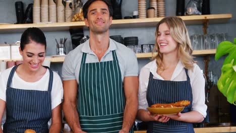 portrait of happy waiters are holding pastries and posing