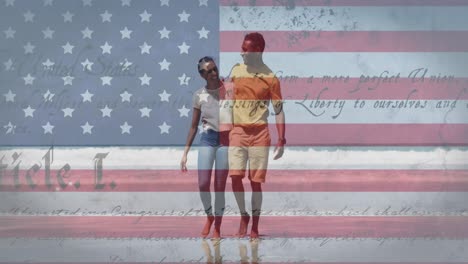 Animation-of-american-flag-and-text-moving-over-couple-walking-on-beach