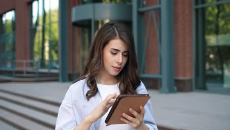 close-up view of caucasian student woman using a tablet in the street