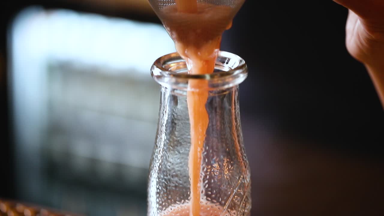 Filtering freshly made juice into a glass bottle