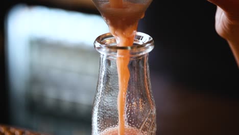 Filtering-freshly-made-juice-into-a-glass-bottle