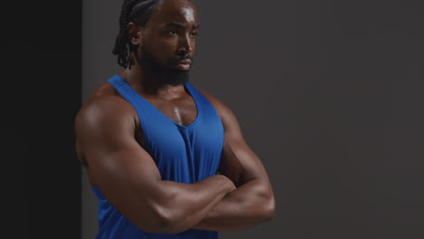 retrato de estudio de un atleta masculino con chaleco sudando después de un entrenamiento deportivo o haciendo ejercicio en el gimnasio doblando los brazos 1