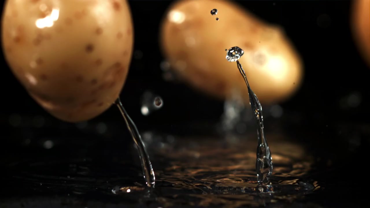Patate fresche che cadono e schizzano nell'acqua su sfondo nero