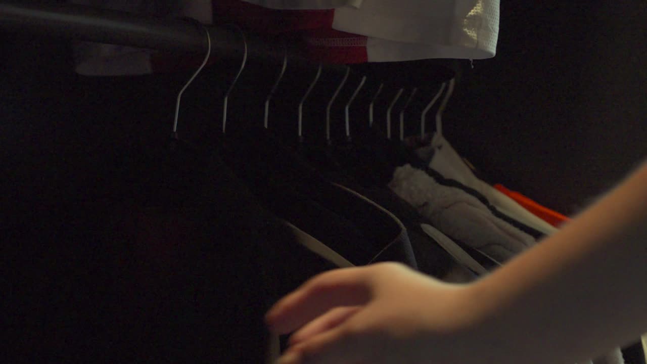 Going through clothing racks in a closet