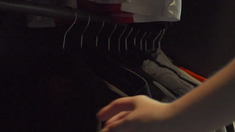pasando por los estantes de ropa en un armario