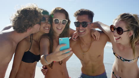 grupo de amigos de raza mixta tomando selfies en la playa usando la cámara del teléfono