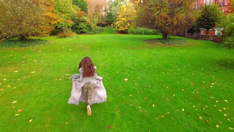 drone chasing young woman with red hair running in autumn park