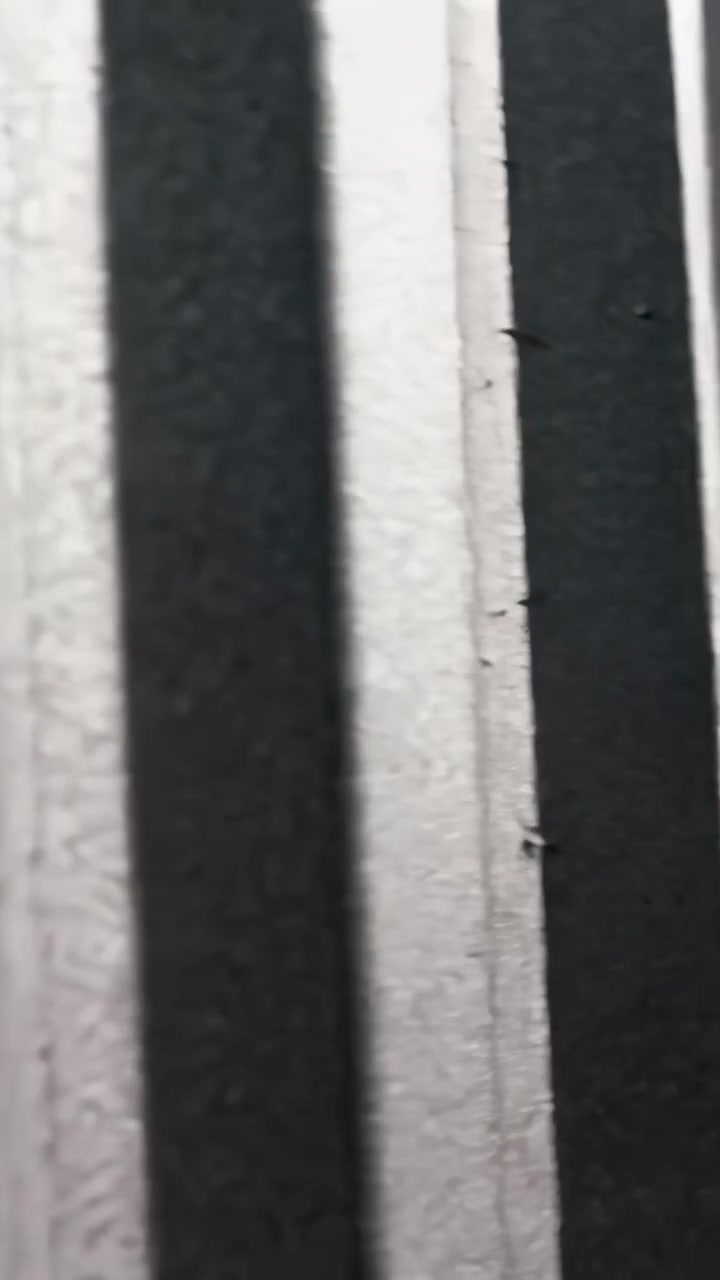 Vertical video: Panning camera inspecting textured slats at panel, revealing gap and specks