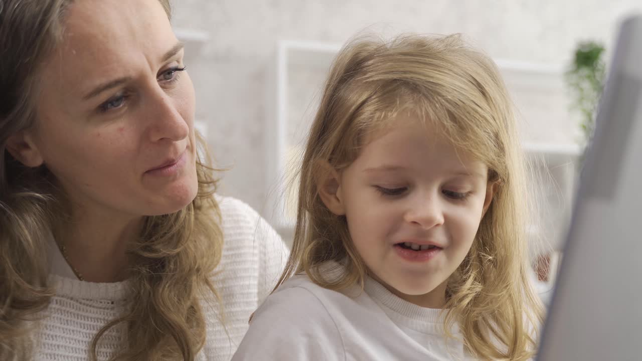 엄마는 노트북에서 일하고 딸은 그녀를 쳐다보고 있습니다.