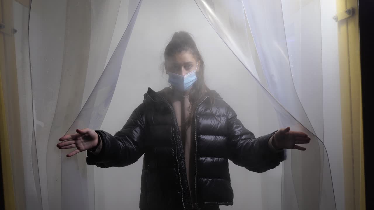 안개로 가득 찬 공간에서 마스크를 착용한 여성.