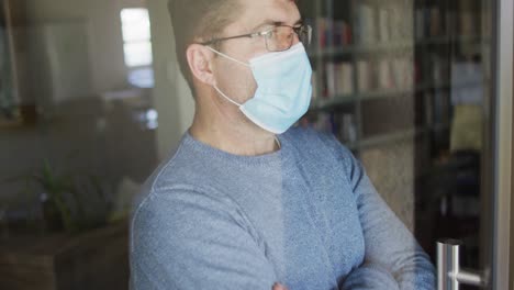 caucasian man wearing face mask, looking through window