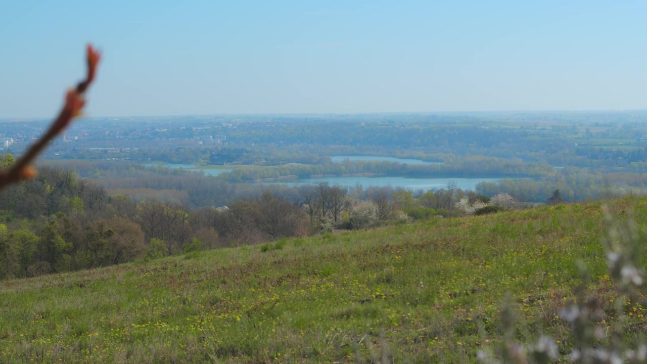 Vue panoramique de la campagne depuis une colline, en pleine nature, s'étendant jusqu'à l'horizon.