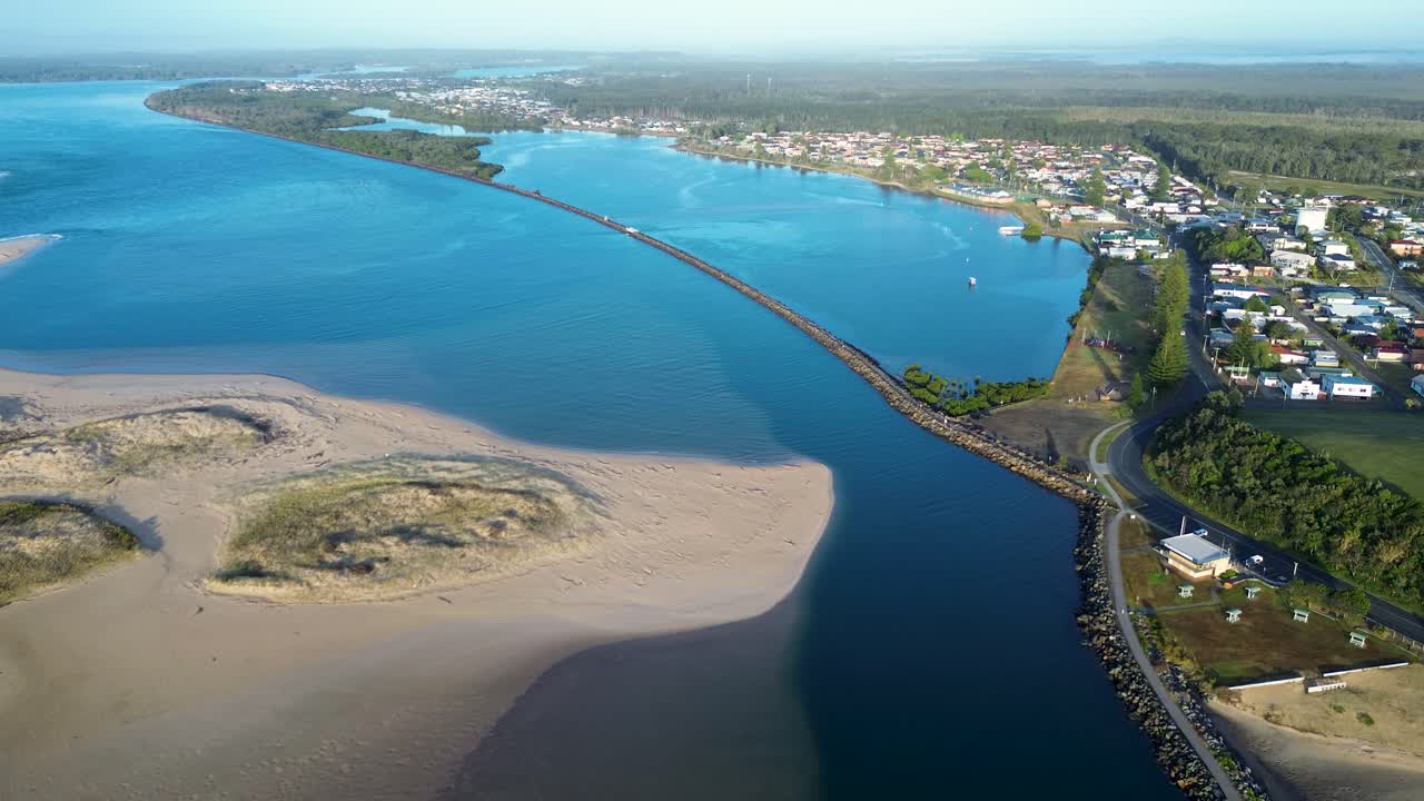 Drone aerial landscape of Manning River environment with pathway river rocky break wall bridge and town suburbs with rural housing along Harrington waterfront near Taree NSW Australia nature holidays